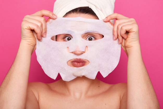 Close up of funny woman looks through white paper mask