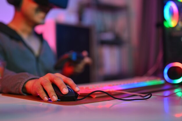 Close up of gamer holding mouse playing video game on computer at home Gaming esports and tournament concept