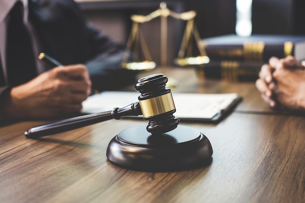 close-up of gavel with lawyer and client discussing paperwork in background