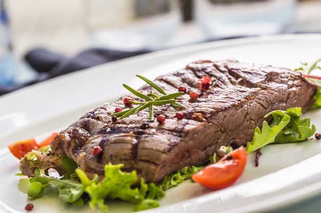 Close-up gedeelte van sappige flank steak van plantaardige salade zout peper en rozemarijn op witte plaat.