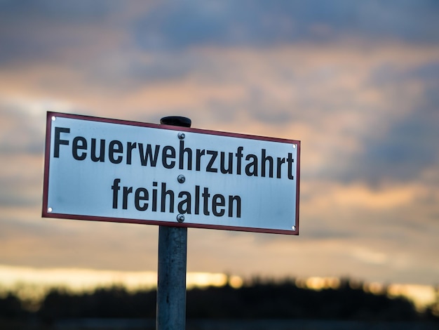 Close-up of german road sign feuerwehrzufahrt freihalten against dramatic sky
