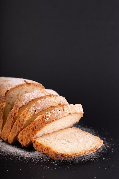 Close-up gesneden Frans mager brood met bloem op een zwarte achtergrond Concept recept van handgemaakt brood