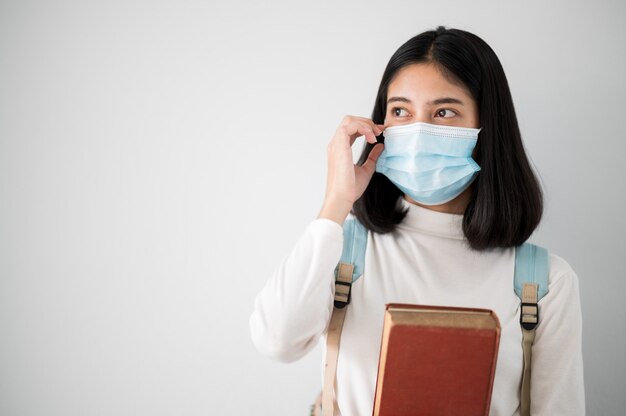 Close-up gezicht portret vrouwelijke aziatische universiteitsstudenten dragen een masker en houden sociale afstanden tijdens schooluren.