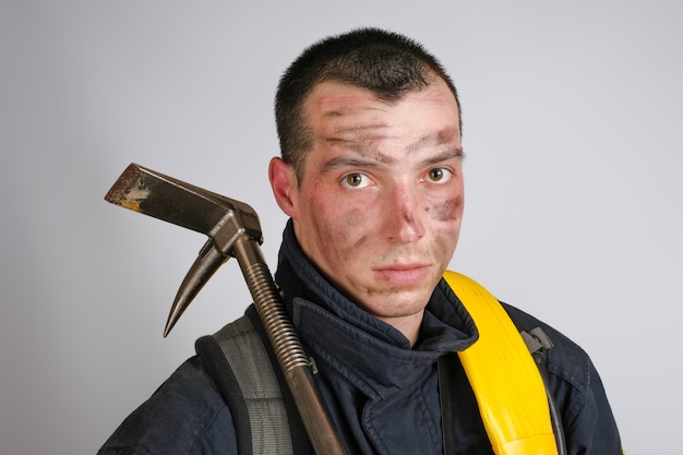 Foto close-up gezicht van dappere jongeman in uniform van brandweerman en koevoet gereedschap