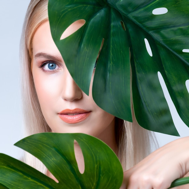 Close-up gezichtsportret knappe vrouw met groene monstera