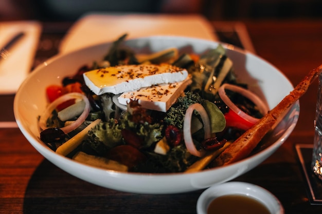 Close-up gezonde groentesalade met een groot stuk kaas, olijfolie, ui en kruiden