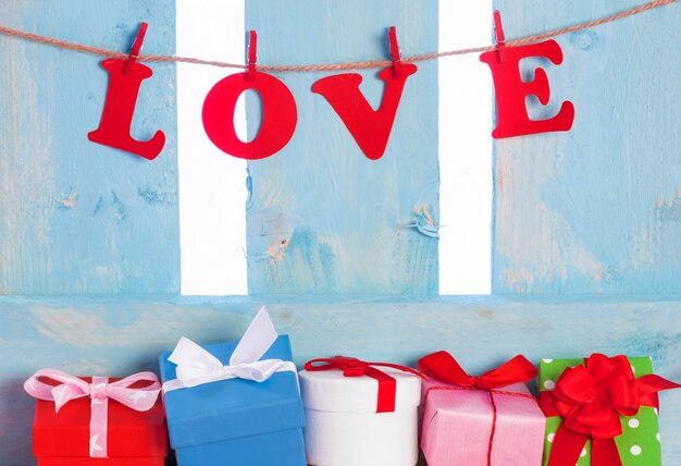 Photo close-up of gifts against love text hanging on wall