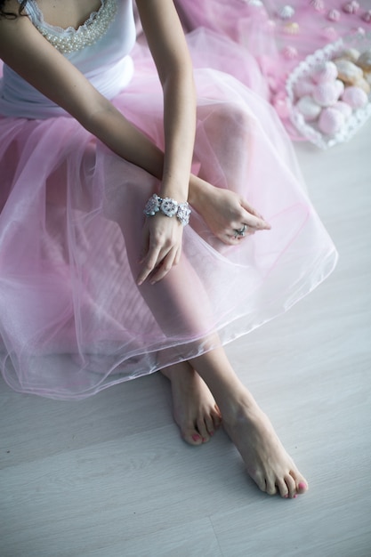 Close-up of a girl bare wrists and legs in a long faceless dress