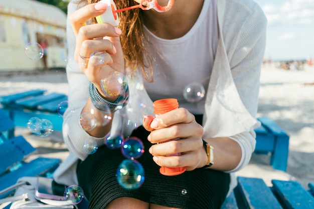 Close-up of a girl blow bubbles on the beach