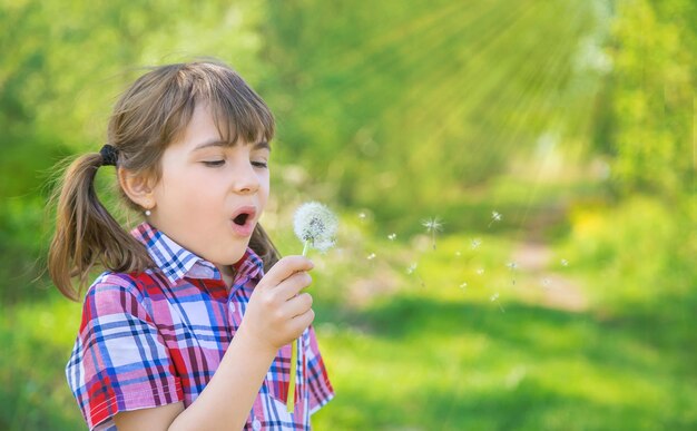 Photo close-up of girl blowing dandelion seed