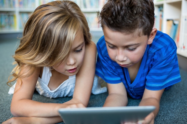 Close-up of girl and boy using digital tablet in library