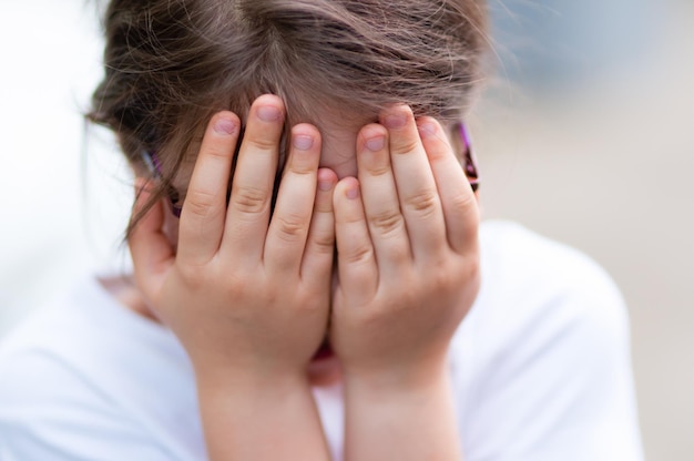 Foto close-up di una ragazza che copre il viso con le mani