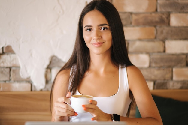 Photo close up of girl drinking cappuccino in the cafe beautiful brunette