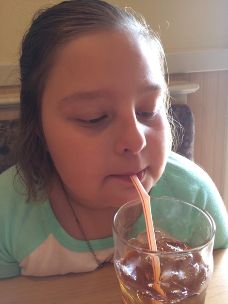 Photo close-up of girl drinking ice tea at home