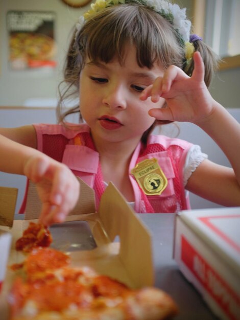 Photo close-up of girl eating pizza on table at restaurant