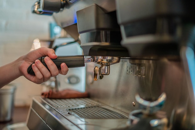 Close up girl hand holding a portafilter with morning coffee Waiter making latte Preparation