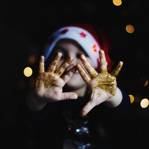 Photo close-up of girl hands covered with glitters in darkroom