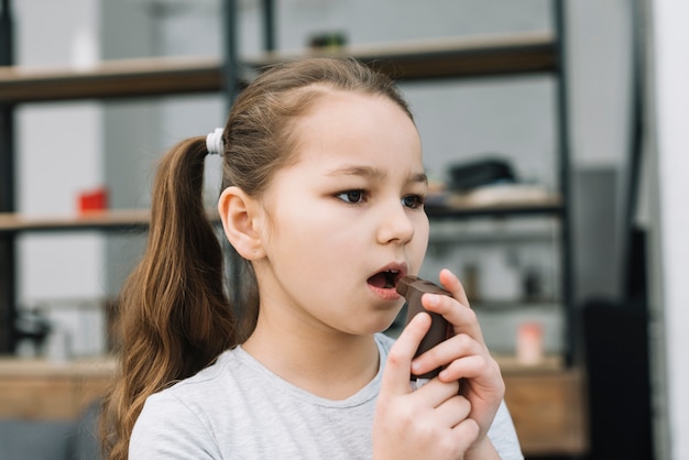 彼女の口の前でぜんそくの吸入器を持って女の子のクローズアップ