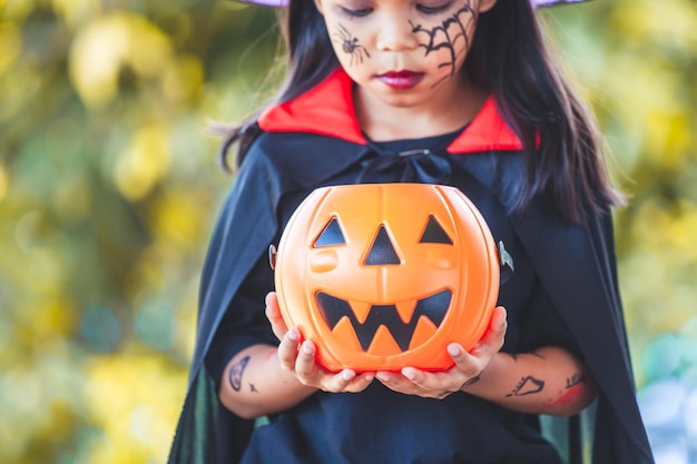 Close-up of girl holding jack o lantern while standing during halloween