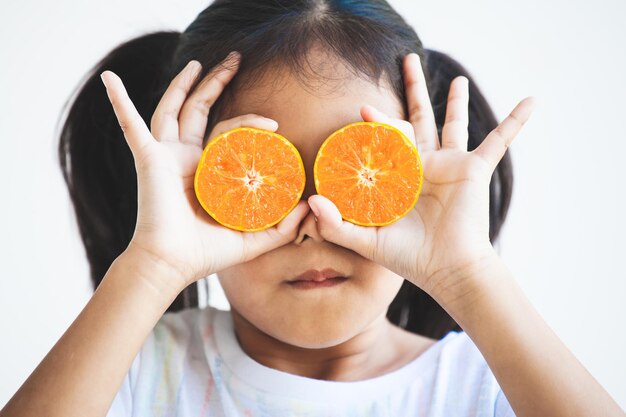 Close-up of girl holding orange over eyes