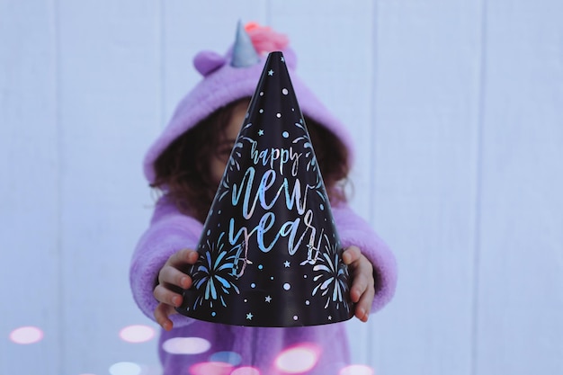 Photo close-up of girl holding party hat against wall