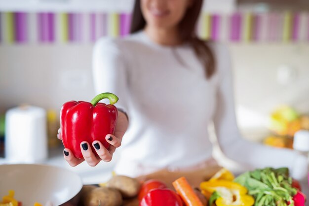 Chiuda in su della ragazza che tiene la paprica rossa in sue mani. il focus è sulla paprika.