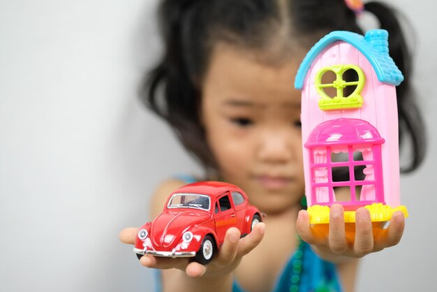 Photo close-up of girl holding toys against wall