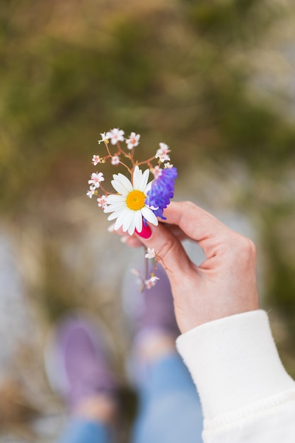 Close-up. The girl holds wildflowers in a hand