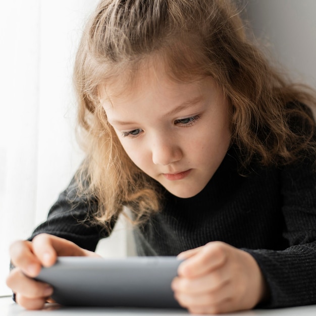 Foto ragazza del primo piano che esamina telefono