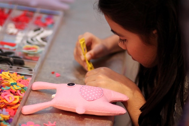 Photo close-up of girl making toy at table