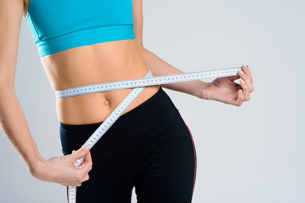 close up. girl measures waist with centimeter.