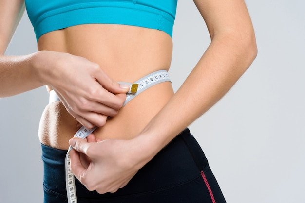 Close Up. Girl Measures Waist With Centimeter.