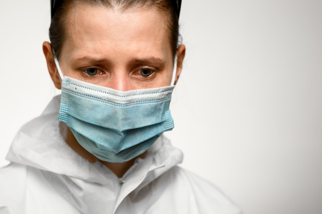 Close-up girl in medical mask with sad expression look down