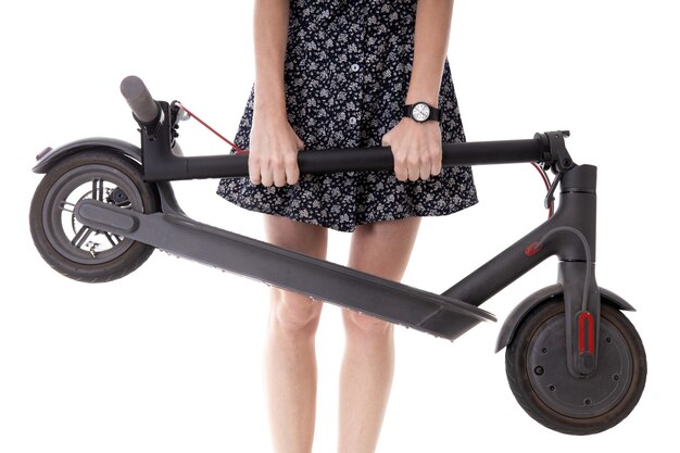 Close-up of a girl's hand holding a folded electric scooter on a white background