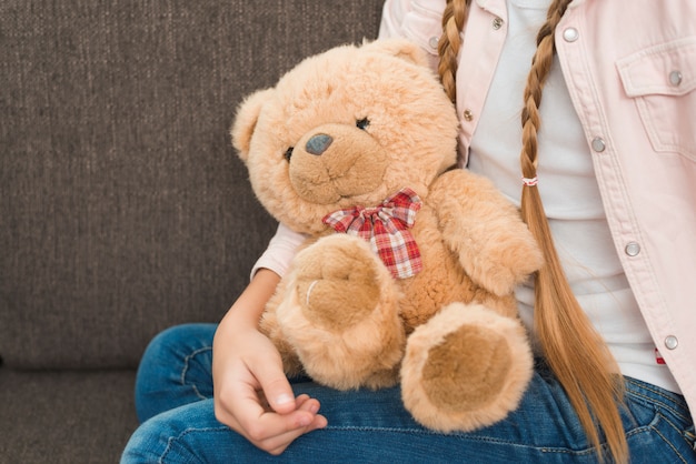 Foto primo piano di una ragazza che si siede sul sofà con gli orsacchiotti farciti molli