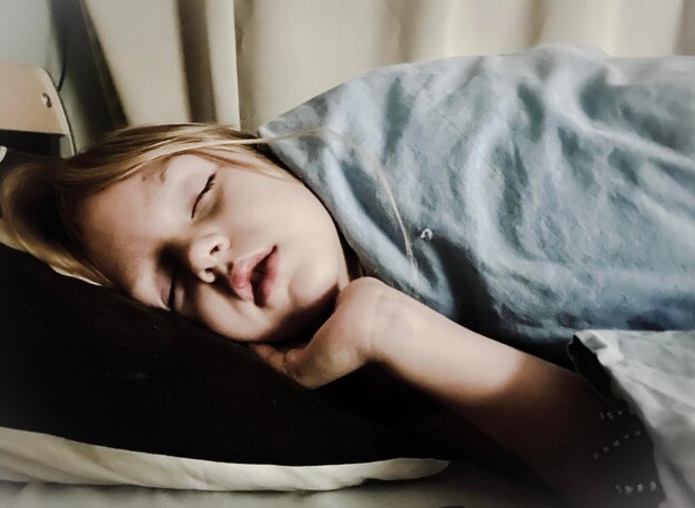 Photo close-up of girl sleeping on bed at home