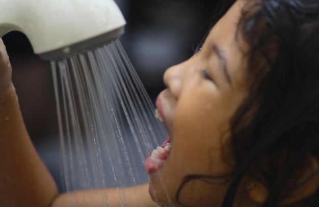 Photo close-up of girl taking bath with shower