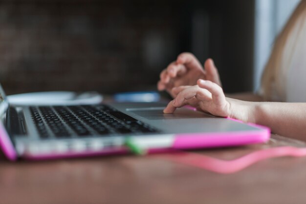 Foto chiuda in su della ragazza che per mezzo del computer portatile