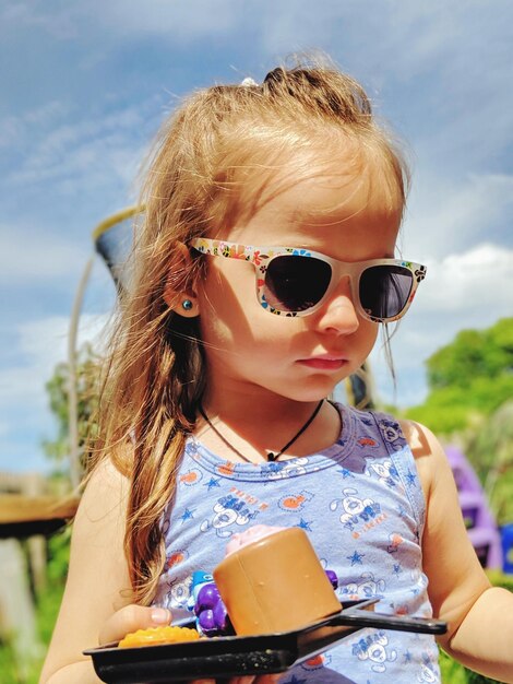 Photo close-up of girl wearing eyeglasses while holding toy at park