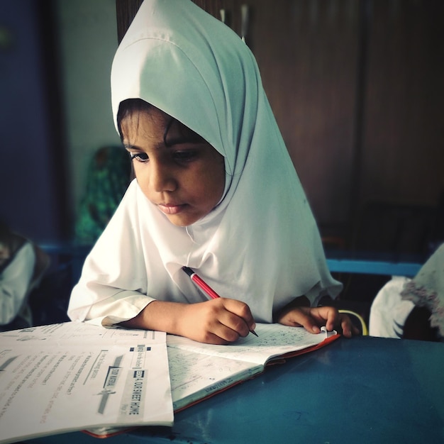 Photo close-up of girl wearing hijab while studying