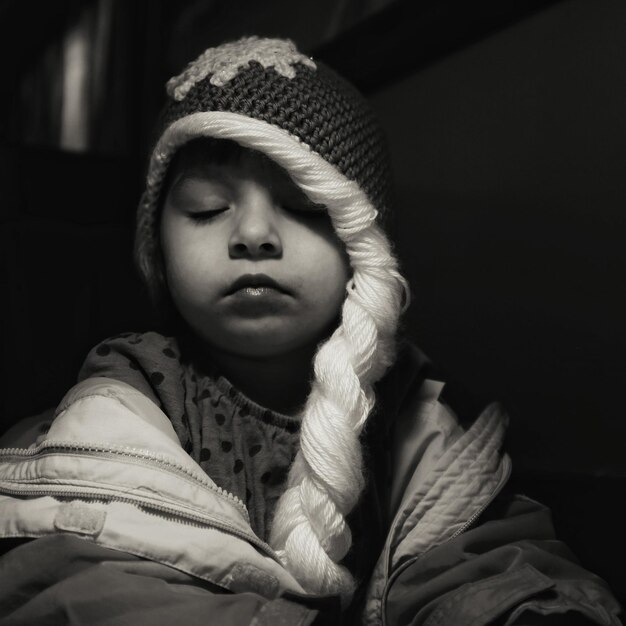 Foto close-up di una ragazza che indossa un cappello a maglia mentre fa un pisolino