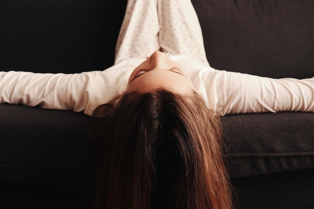 close-up of girl with arms outstretched while lying on sofa at home