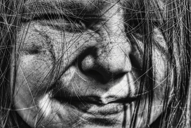 Close-up of girl with hair on face smiling on sunny day