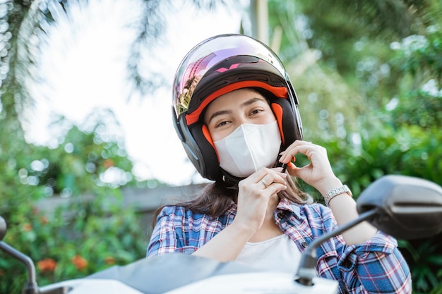 Close up of girl with mask tying the helmet safety strap before riding a motorbike