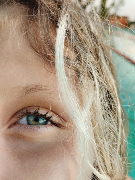 Photo close-up of girls blue eye near blue water