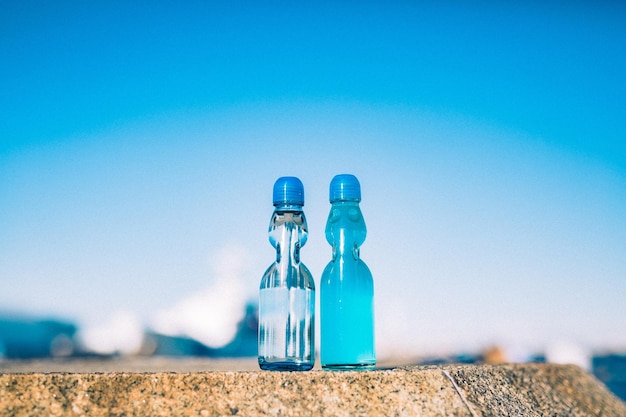 Close-up of glass bottle against blue sky