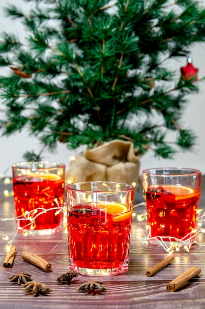 Close-up of a glass of  hot mulled red wine , on a wooden table with a Christmas tree