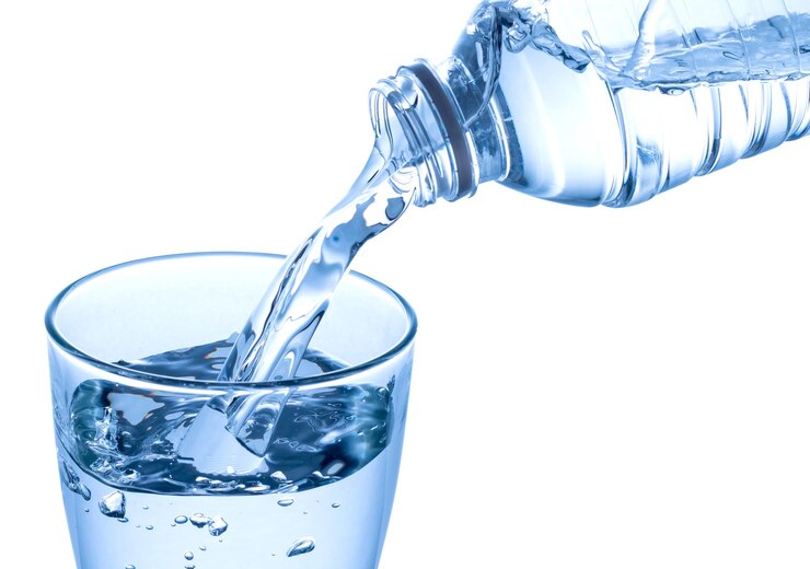 Photo close-up of glass pouring water against white background