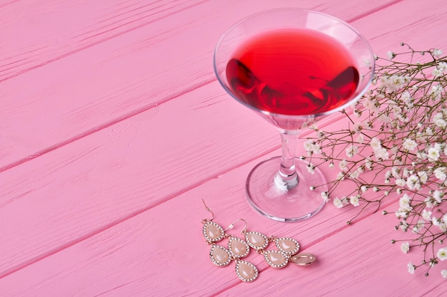 Close up glass of red martini with earrings