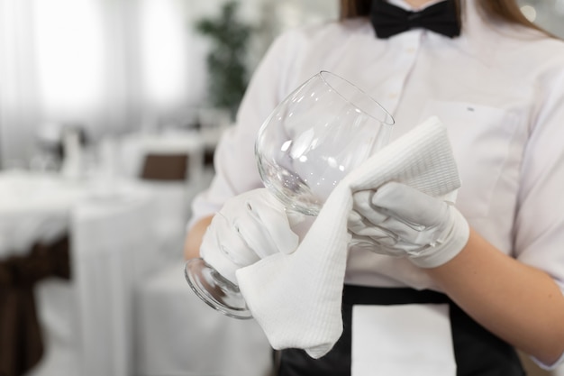 Close-up of a glass and a towel in the hands of a waiter. Preparation, table setting.